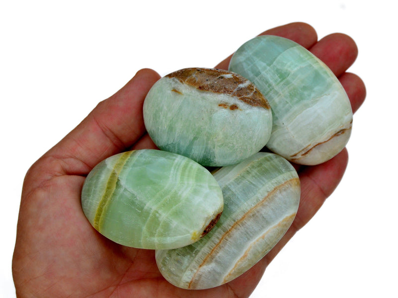 Four pistachio calcite palm stones 55mm-70mm on hand with white background