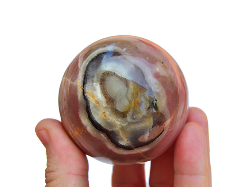 One pink banded onyx crystal ball 55mm on hand with white background