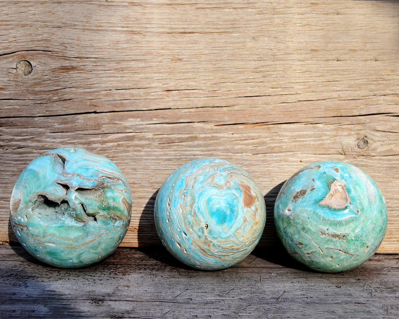 Trhee extra large blue aragonite sphere crystals with wood background