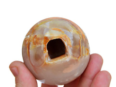 One pink banded onyx crystal ball 60mm on hand with white background
