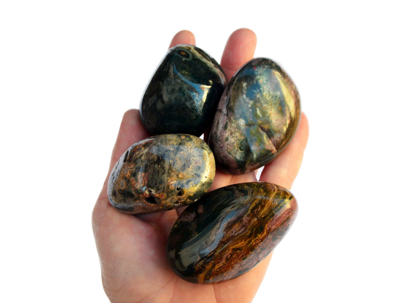 Four big ocean jasper tumbled stones on hand with white background