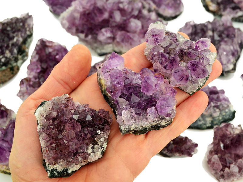 Three amethyst druzy stones 50mm-70mm on hand with background with some stones on white