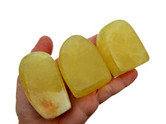 Three lemon calcite free form crystals 50mm-70mm on hand with white background