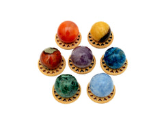 Mini spheres of polychrome jasper, carnelian, yellow septaria, chrysocolla, blue calcite, blue apatite and amethyst stones 30mm forming a circle on wooden bases on a white background.