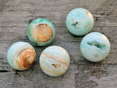Five large caribbean blue calcite spheres 80mm-85mm on wood table