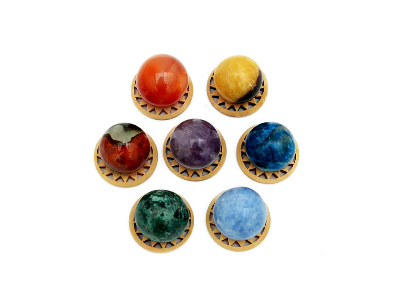Mini spheres of polychrome jasper, carnelian, yellow septaria, chrysocolla, blue calcite, blue apatite and amethyst stones 30mm forming a circle on wooden bases on a white background.
