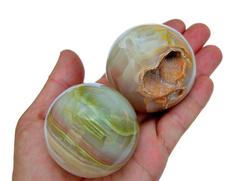Two pink banded onyx crystal balls 55mm-60mm on hand with white background