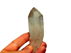One natural clear quartz point 80mm on hand with white background