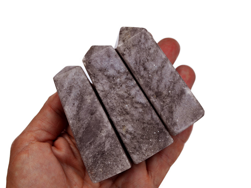 Three purple lepidolite obelisk crystals 60mm-65mm on hand with white backround