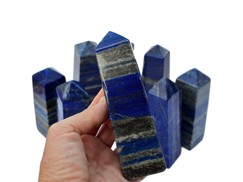 One large lapis lazuli tower on hand with background with some towers on white
