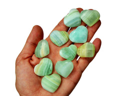 Ten green pistachio calcite crystal hearts 25mm-30mm on hand with white background