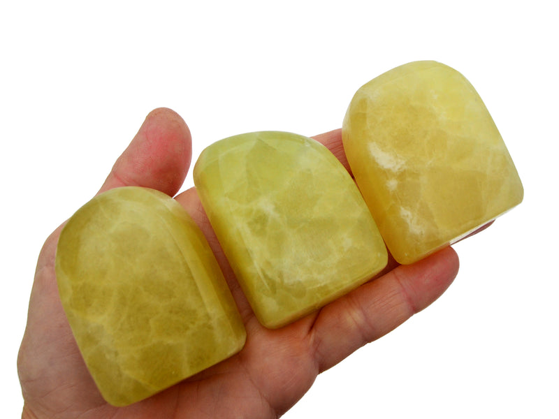 Three lemon calcite free form minerals 50mm-70mm on hand with white background