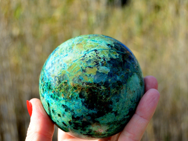 Big chrysocolla sphere 70mm on hand with baackground with plants