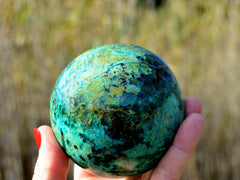Big chrysocolla sphere 70mm on hand with baackground with plants