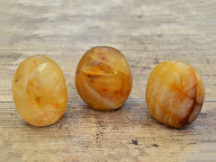 Three golden healer quartz free forms on wood table