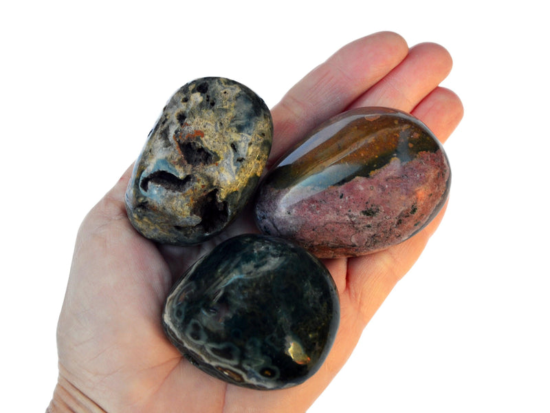 Three big ocean jasper tumbled stones on hand with white background