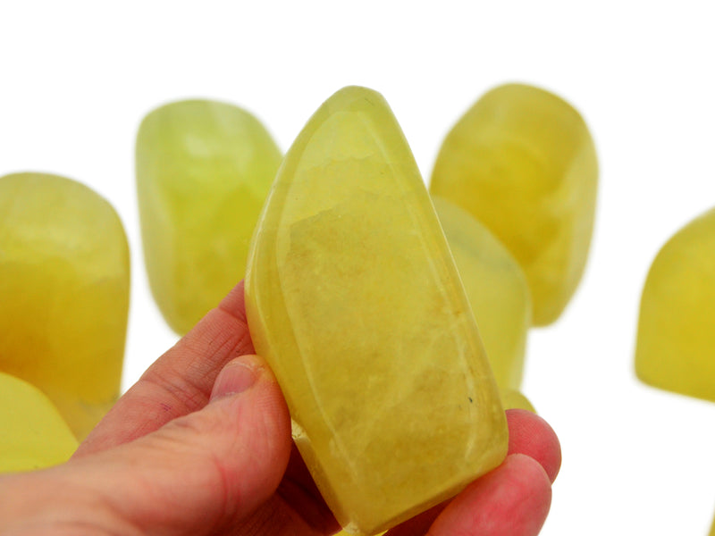 One lemon calcite free form stone 80mm on hand with white background