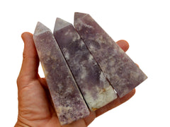 Three large purple lepidolite crystal towers 90mm-100m on hand with white background