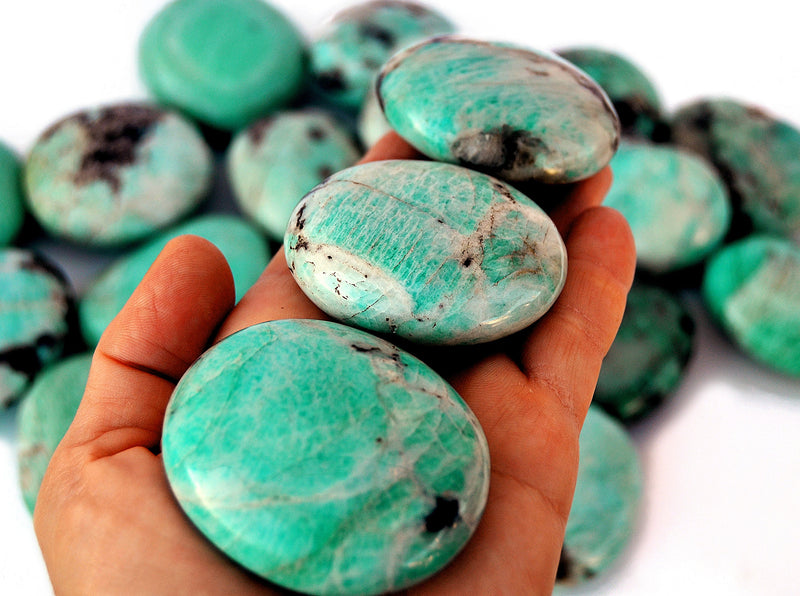 Three amazonite palm stones 60mm-40mm on hand with background with some stones on white  background