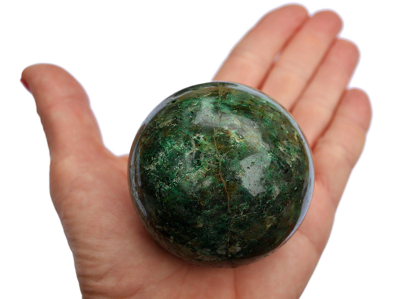 One green chrysocolla sphere 55mm on hand with background with some crystals inside a snd with white background 
