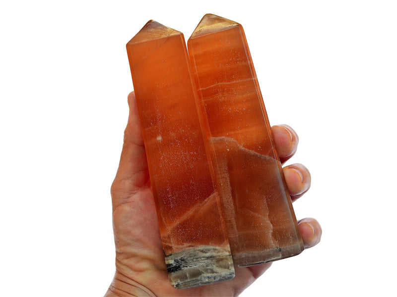 Two large chuny honey calcite crystal obelisks 140mm on hand with white background