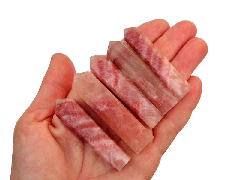Five rose calcite faceted points 55mm-65mm on hand with white background