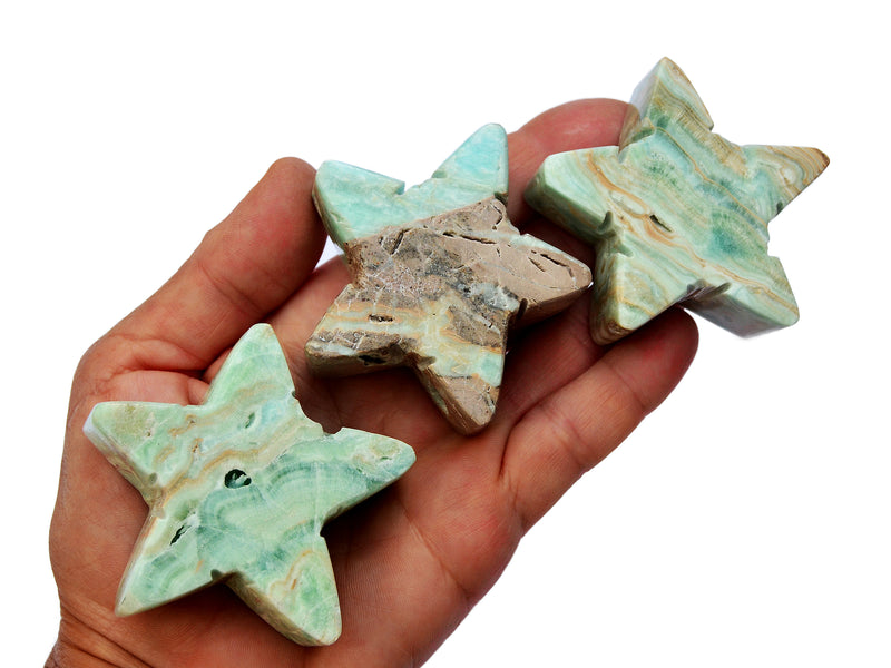 Three blue aragonite stars 60mm on hand with white background