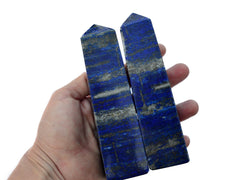 Two large lapis lazuli obelisks crystals on hand with white background