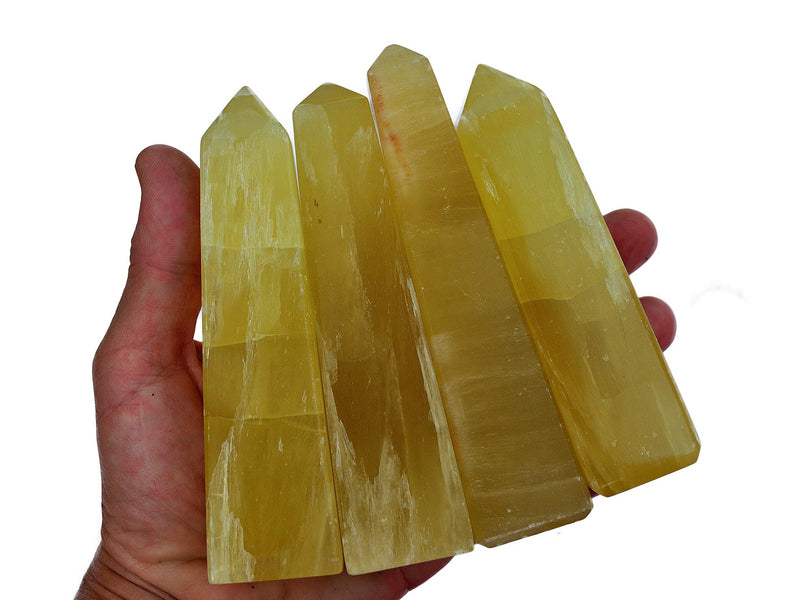 Four large lemon yellow calcite towers 100mm on hand with white background