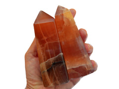 Two large honey calcite crystal towers 100mm on hand with white background