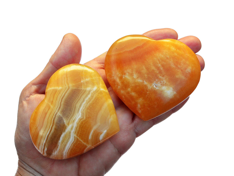 Two orange calcite crystal stones 60mm-75mm on hand with white background