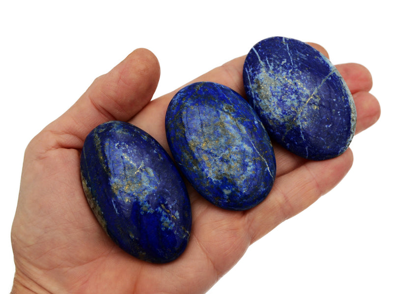 Three lapis lazuli palm stone crystals 55mm-60mm on hand with white backround