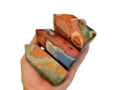 Three small polychrome jasper towers on hand with white background