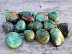 Several large green chrysocolla tumbled minerals on wood table