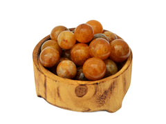 Several golden healer quartz small spheres inside a wood bowl on white background