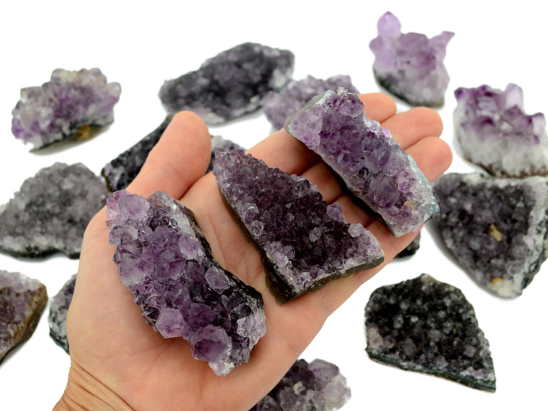 Three amethyst crystal clusters 80mm on hand with background with some druzy crystals on white
