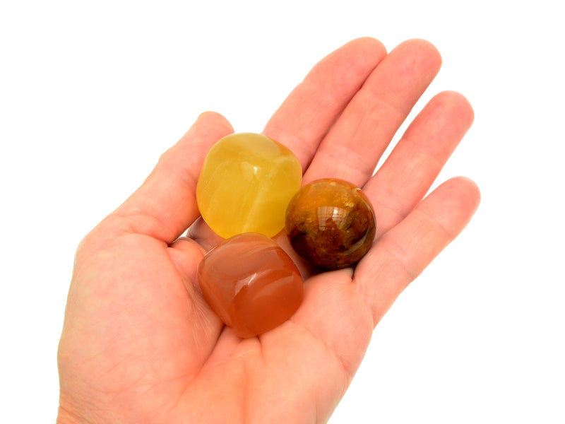 Lemon calcite and honey calcite tumbled crystals with golden healer quartz sphere 30mm on hand with white background
