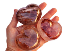 Three big fire quartz carved heart stones 67mm on hand with white background