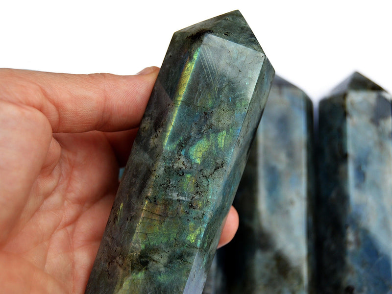 One large labradorite obelisk 110mm on hand with background with some towers