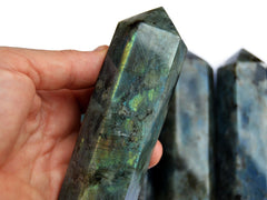 One large labradorite obelisk 110mm on hand with background with some towers