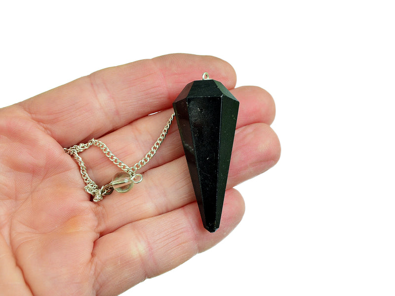 One black tourmaline crystal pendulum with silver chain on hand with white background