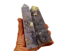 Three large purple lepidolite obelisk crystals on hand with white background