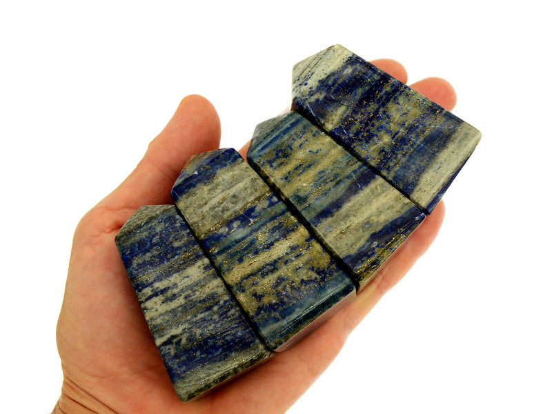 Four lapis lazuli crystal obelisks 60mm on hand with white background