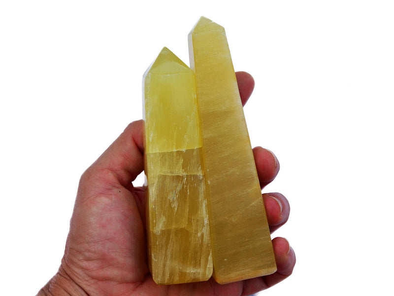Two lemon calcite crystal obelisks 150mm on hand with white background