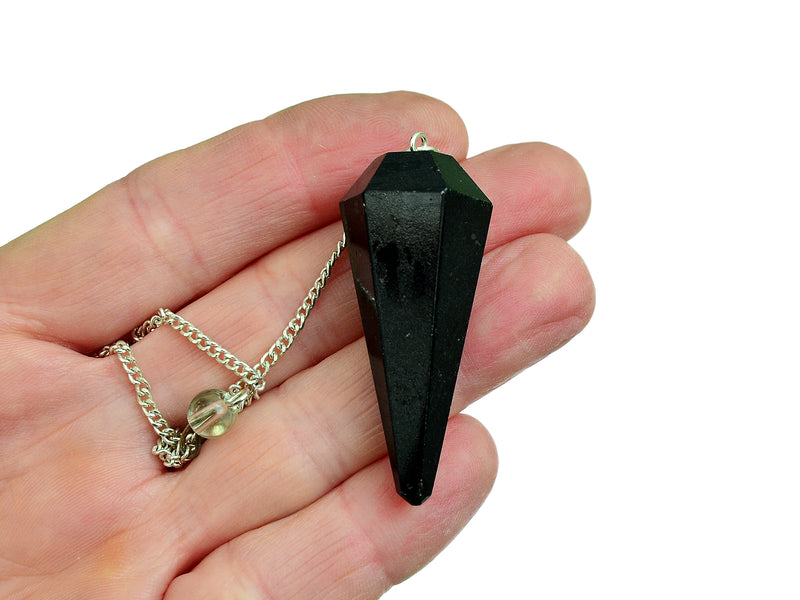 lack tourmaline faceted point pendulum with silver chain on hand with white background