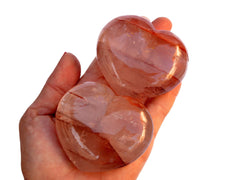 Two large fire quartz heart crystals 67mm on hand with white background