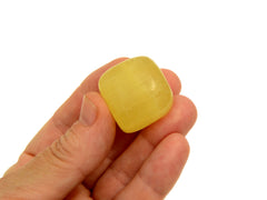 Lemon calcite tumbled stone 20mm on hand with white background