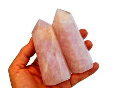 Two pink quartz tower crystals on hand with white background