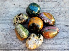 Seven large ocean jasper tumbled stones on wood table