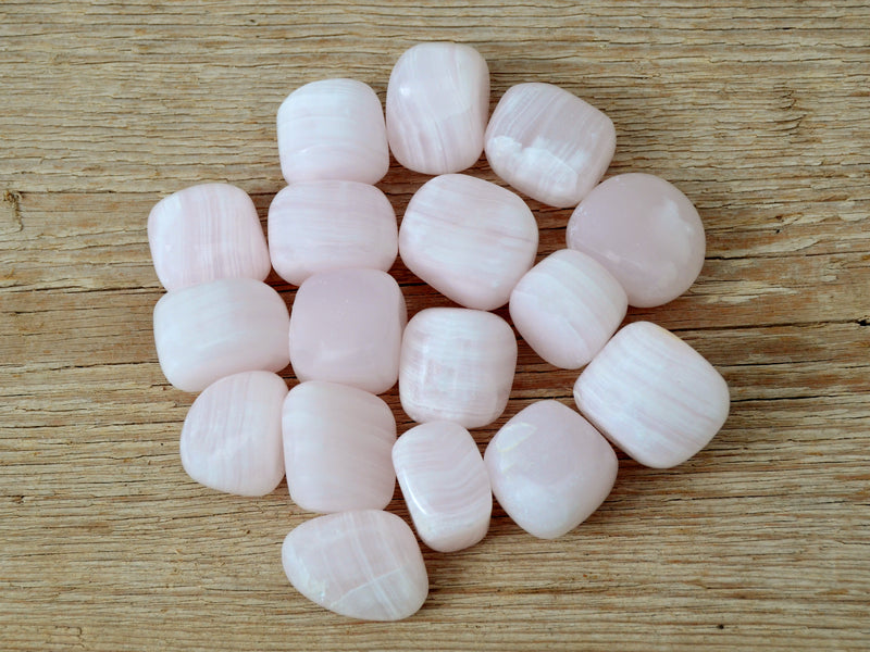 Some pink mangano calcite mini tumbled crystals 20mm-30mm on wood table